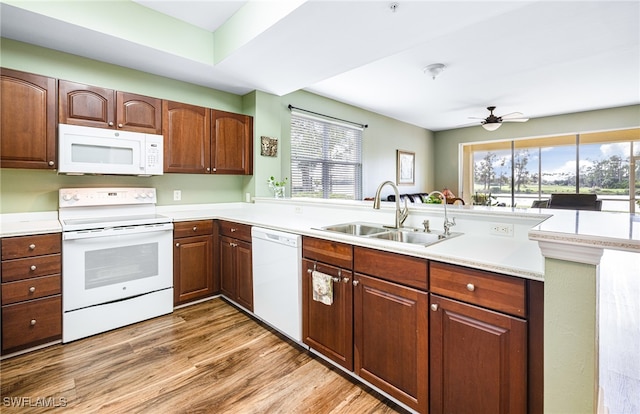 kitchen featuring a peninsula, white appliances, light countertops, and a sink