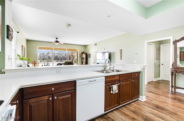 kitchen featuring dark brown cabinetry, dishwasher, light wood-style flooring, light countertops, and a sink