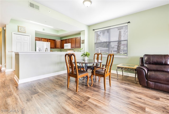 dining area with light wood finished floors, visible vents, and baseboards