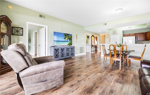 living area featuring light wood-style flooring, visible vents, and baseboards