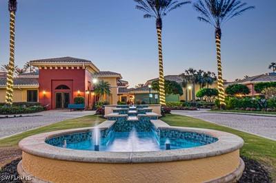 pool at dusk featuring a pool with connected hot tub