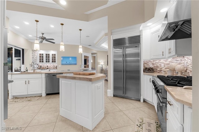 kitchen featuring wall chimney exhaust hood, a center island, high quality appliances, and backsplash