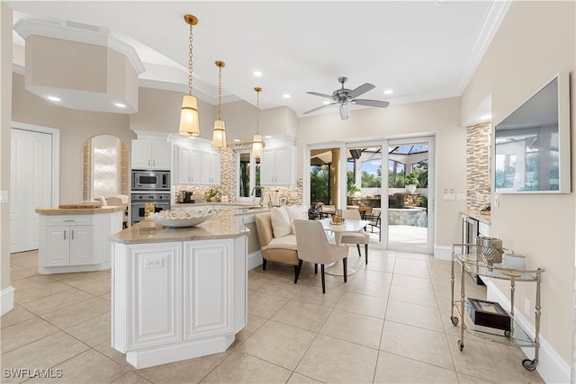 kitchen with ceiling fan, decorative light fixtures, a kitchen island, white cabinetry, and stainless steel appliances