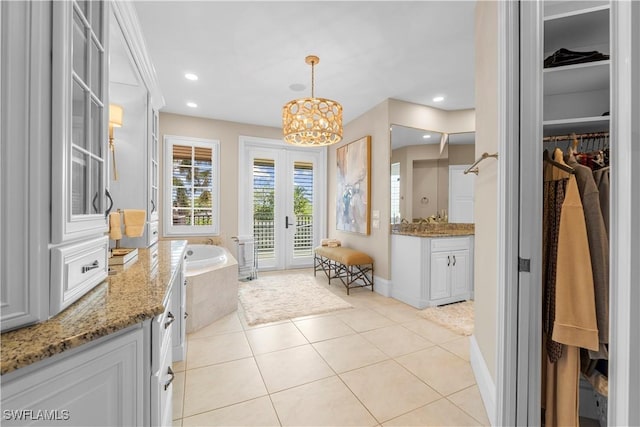 bathroom with french doors, tile patterned floors, vanity, tiled tub, and a notable chandelier