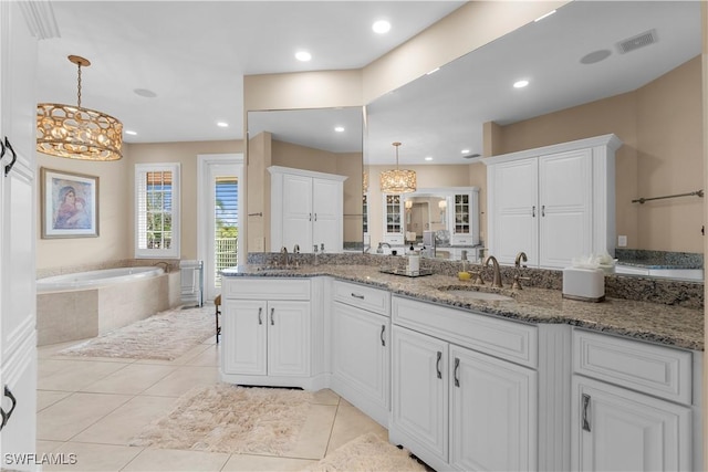 kitchen with light stone counters, sink, white cabinets, and hanging light fixtures