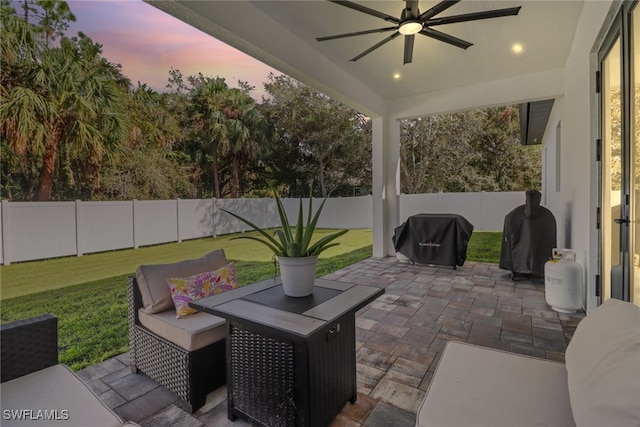 patio terrace at dusk with a lawn, a grill, and ceiling fan