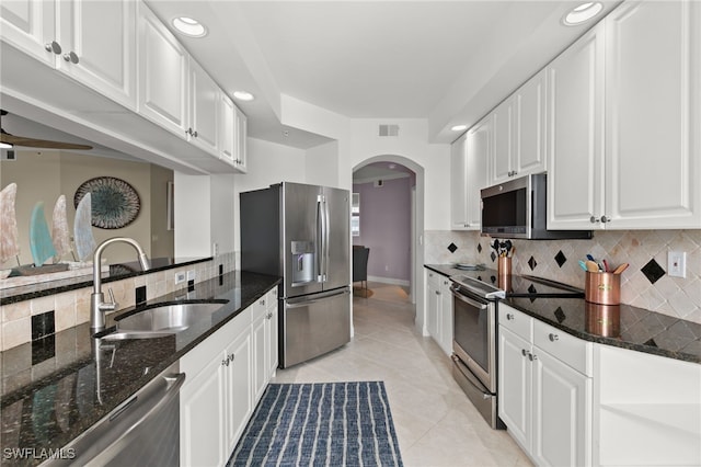 kitchen with white cabinetry, sink, stainless steel appliances, dark stone countertops, and light tile patterned floors