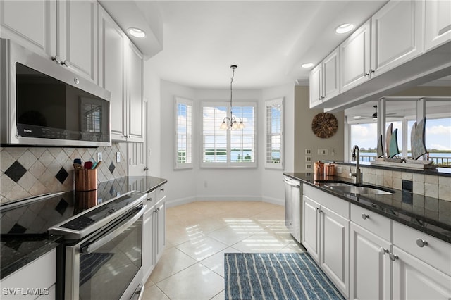 kitchen featuring appliances with stainless steel finishes, light tile patterned floors, an inviting chandelier, and white cabinetry