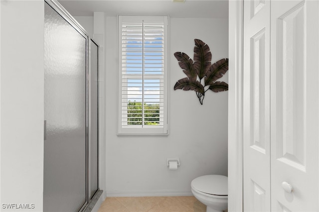 bathroom featuring tile patterned flooring, toilet, and a shower with door