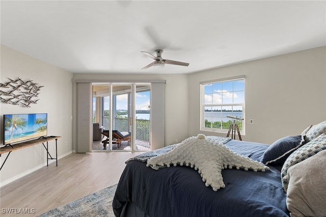 bedroom featuring access to exterior, light wood-type flooring, a water view, and ceiling fan