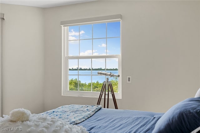 bedroom with multiple windows and a water view