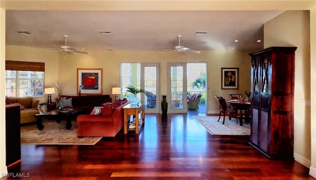 living room with a wealth of natural light, dark wood-type flooring, and ceiling fan