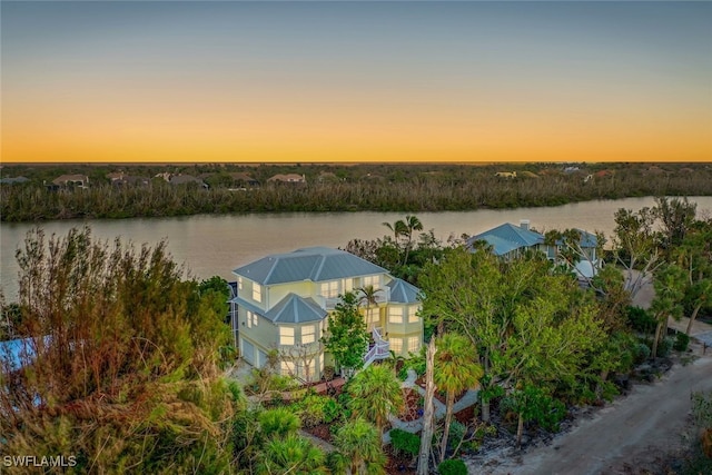 aerial view at dusk featuring a water view