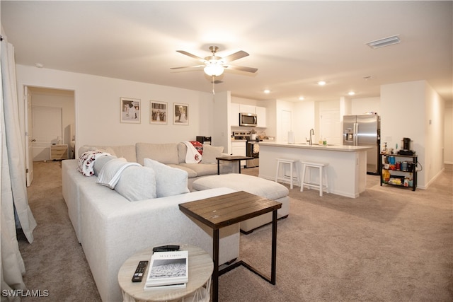 living room featuring light carpet, ceiling fan, and sink