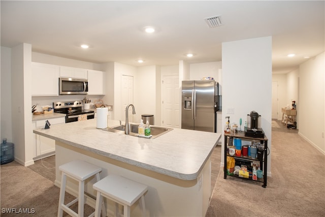 kitchen featuring light carpet, appliances with stainless steel finishes, a kitchen island with sink, sink, and white cabinets