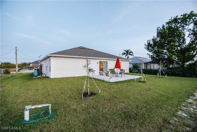 back of house with a lawn and a patio