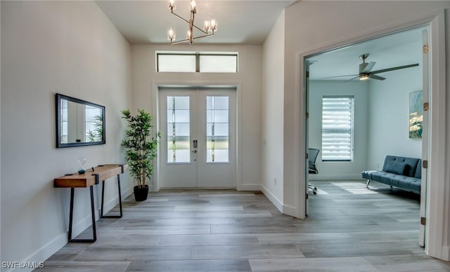 entryway featuring a wealth of natural light, light hardwood / wood-style flooring, ceiling fan with notable chandelier, and french doors