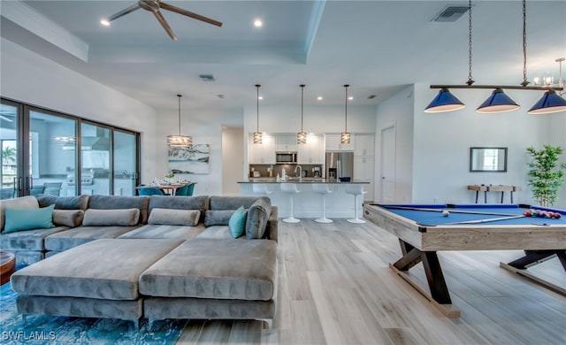 rec room with ornamental molding, a tray ceiling, ceiling fan, billiards, and light hardwood / wood-style floors