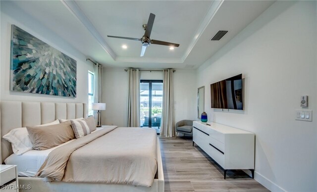 bedroom featuring a raised ceiling, ceiling fan, access to outside, and light wood-type flooring