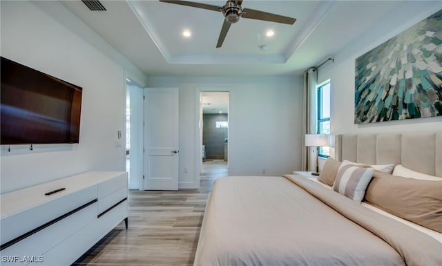 bedroom with ceiling fan, a raised ceiling, and light hardwood / wood-style flooring