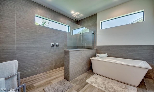 bathroom featuring hardwood / wood-style floors, separate shower and tub, and tile walls