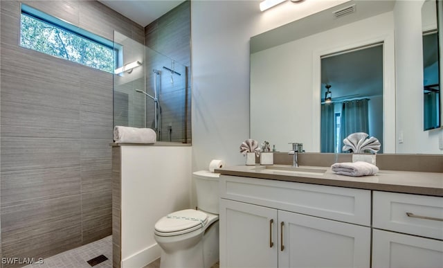 bathroom featuring vanity, toilet, and a tile shower