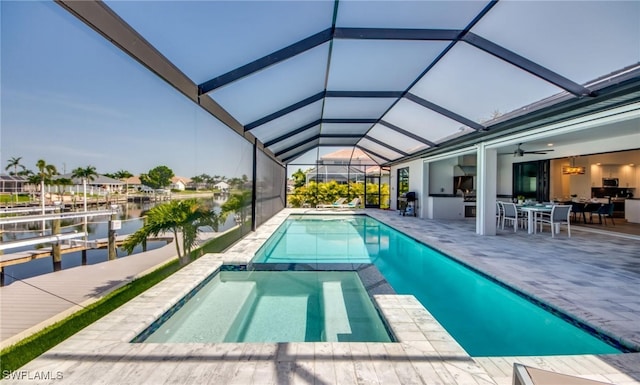 view of pool featuring glass enclosure, a patio area, and a water view