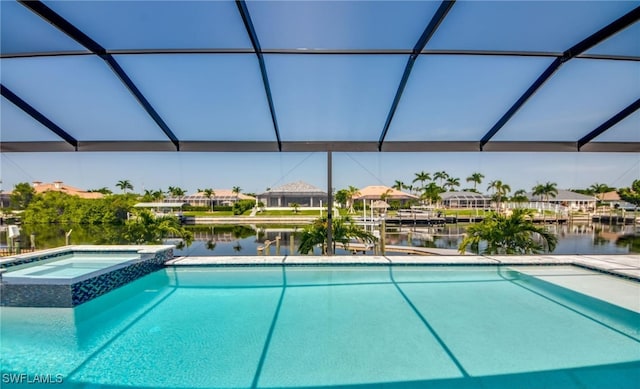 view of pool featuring glass enclosure, an in ground hot tub, and a water view