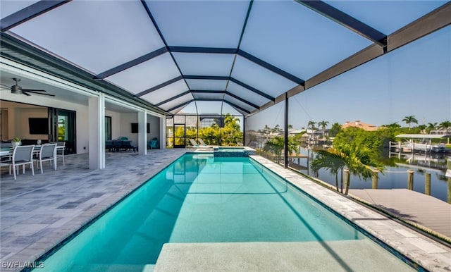 view of pool featuring a water view, ceiling fan, a lanai, an in ground hot tub, and a patio area