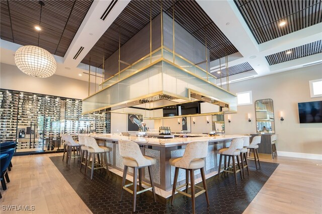 kitchen with wood-type flooring, a towering ceiling, hanging light fixtures, and a breakfast bar area