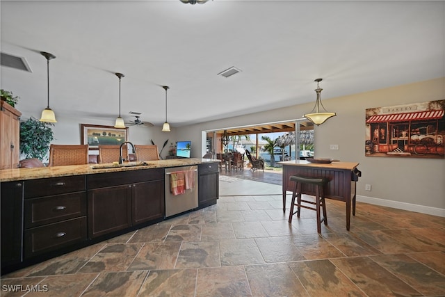 kitchen featuring ceiling fan, dishwasher, sink, light stone counters, and pendant lighting