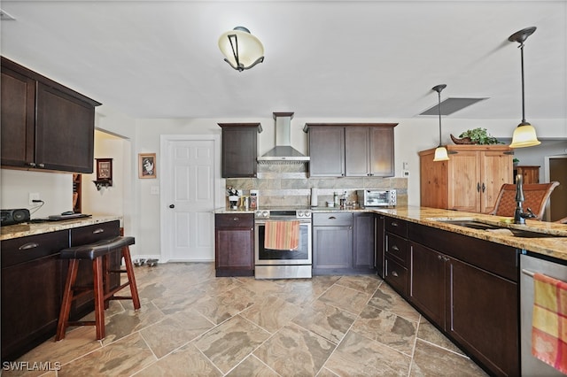 kitchen with sink, wall chimney exhaust hood, decorative backsplash, appliances with stainless steel finishes, and decorative light fixtures