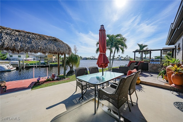 view of patio with an outdoor kitchen, a water view, and a dock