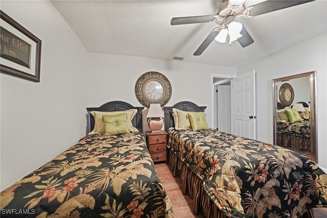 bedroom with ceiling fan, light wood-type flooring, and a textured ceiling