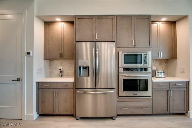 kitchen with decorative backsplash, appliances with stainless steel finishes, and light hardwood / wood-style flooring