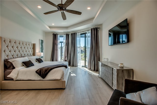 bedroom featuring a raised ceiling, ceiling fan, access to outside, and light wood-type flooring