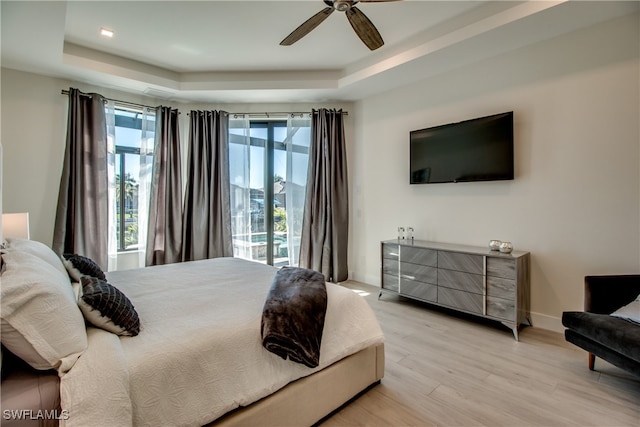 bedroom with a raised ceiling, access to exterior, ceiling fan, and light hardwood / wood-style flooring