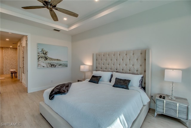 bedroom featuring a raised ceiling, ceiling fan, and light hardwood / wood-style floors