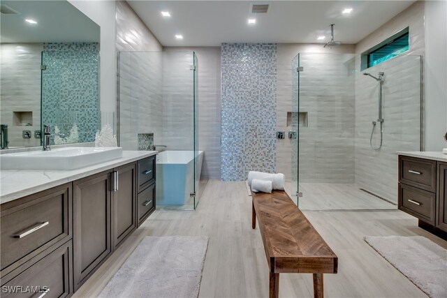 bathroom with hardwood / wood-style floors, vanity, separate shower and tub, and tile walls