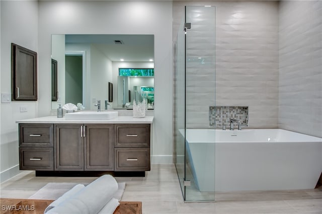 bathroom featuring vanity and independent shower and bath