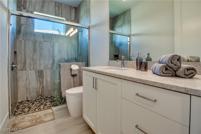 bathroom with hardwood / wood-style flooring, toilet, vanity, and walk in shower