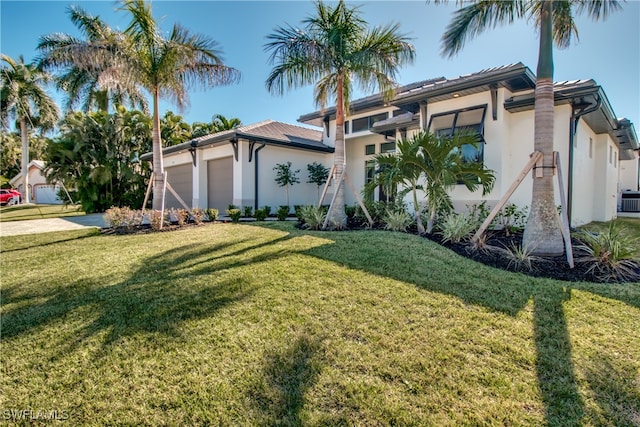 view of front of house featuring central AC unit, a front yard, and a garage