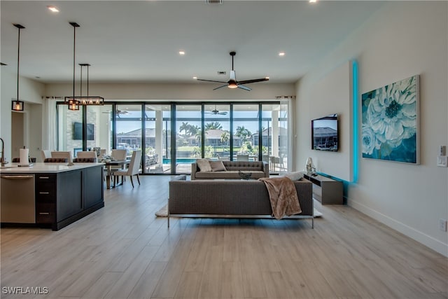 living room with plenty of natural light, ceiling fan, light wood-type flooring, and sink