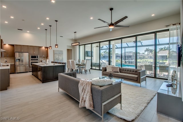 living room with ceiling fan, sink, and light hardwood / wood-style flooring