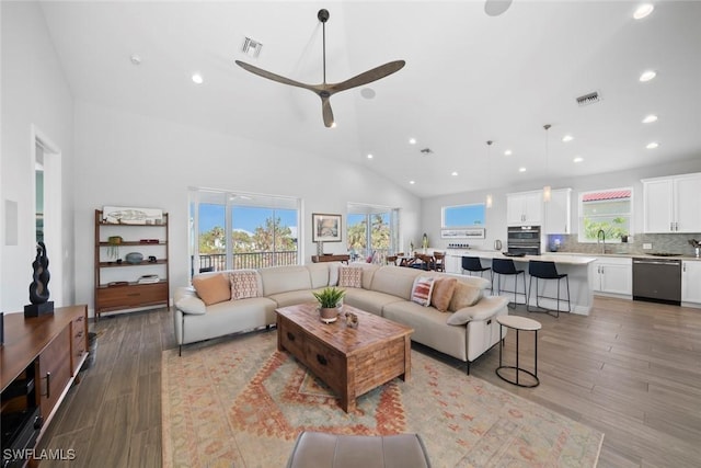 living room with ceiling fan, sink, light hardwood / wood-style floors, and vaulted ceiling