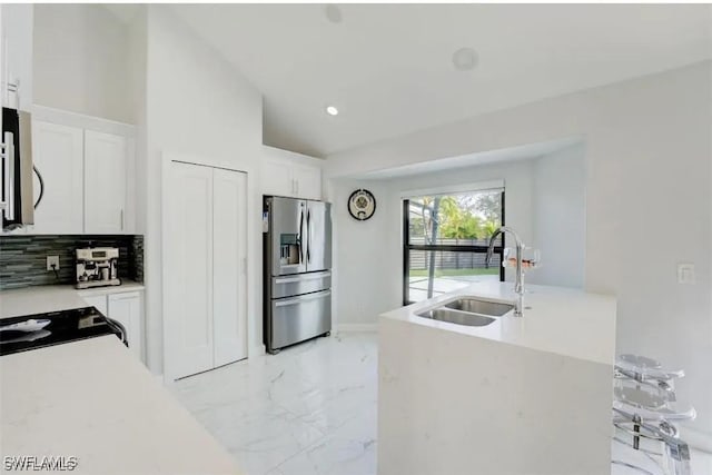 kitchen with sink, white cabinetry, backsplash, and stainless steel appliances