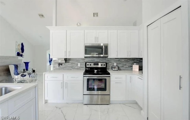 kitchen featuring white cabinets, decorative backsplash, and stainless steel appliances