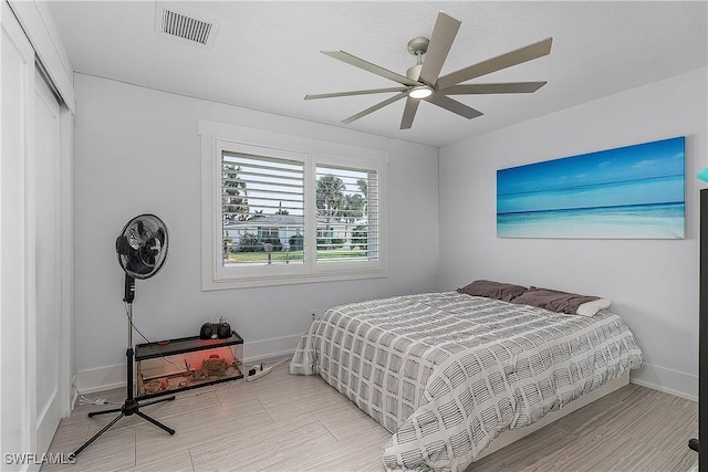 bedroom with a closet, light hardwood / wood-style flooring, and ceiling fan