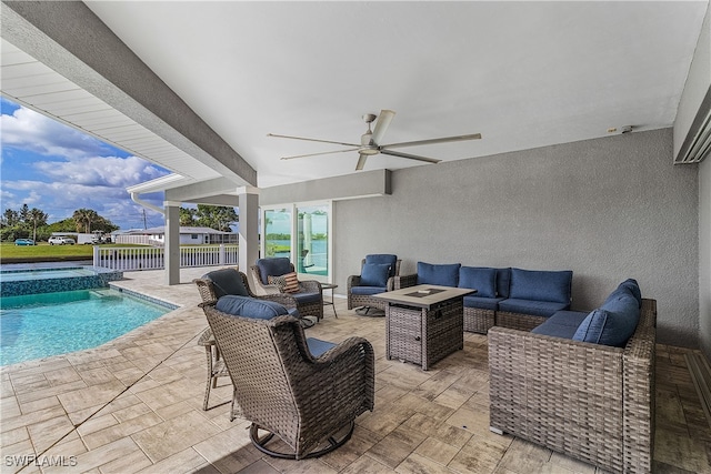 view of patio with ceiling fan, an outdoor living space with a fire pit, and a pool with hot tub