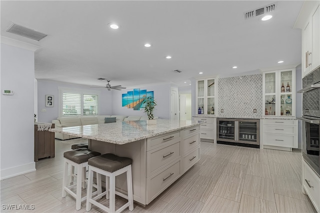 kitchen featuring tasteful backsplash, white cabinetry, a center island, and beverage cooler